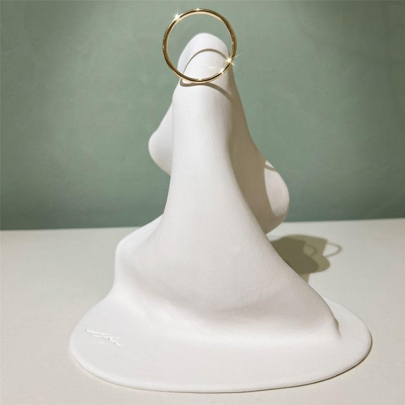 Manto de Maria branco com auréola dourada sobre fundo verde
